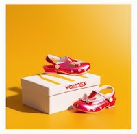 a pair of pink shoes in a box on a yellow background