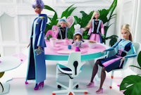 a group of barbie dolls sitting around a table
