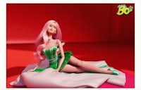 a barbie doll with pink hair laying on a bed