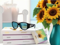 a pair of sunglasses on a table next to a vase of sunflowers